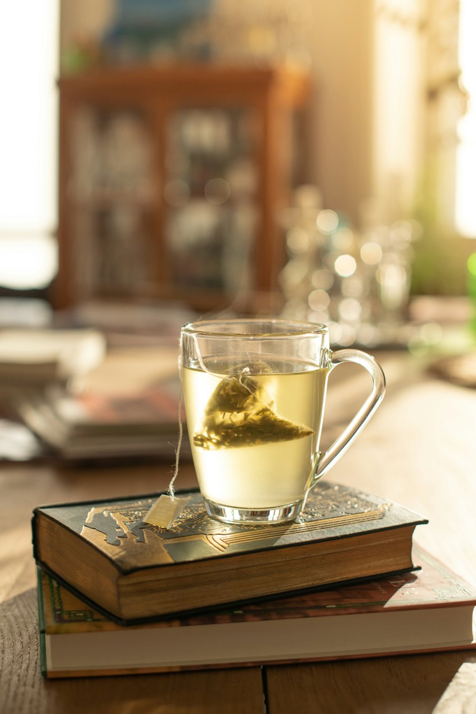 Steaming mug of tea infusing on vintage books.
